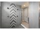 Modern shower with gray tiling, stylish chevron pattern, and glass enclosure in a luxurious bathroom at 8010 Blue River Ave, Littleton, CO 80125