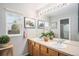 Well-lit bathroom features double sinks, wood cabinets, large mirror, and a window providing natural light at 13340 Saint Paul St, Thornton, CO 80241