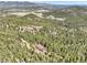 Breathtaking aerial view of a secluded home nestled amidst lush greenery and rolling hillsides and the mountains in the background at 33121 Lynx Ln, Evergreen, CO 80439