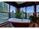 Luxurious bathroom featuring a soaking tub with views of lush greenery and mountain scenery at 33121 Lynx Ln, Evergreen, CO 80439