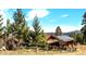 Exterior shot of a mountain home with mature trees, a rustic fence and solar panels at 33121 Lynx Ln, Evergreen, CO 80439