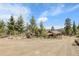 Rustic property entrance showcasing a dirt driveway and wooden fencing, surrounded by lush green trees at 33121 Lynx Ln, Evergreen, CO 80439