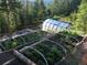 Raised garden beds with plants under netting and a greenhouse in the background at 33121 Lynx Ln, Evergreen, CO 80439