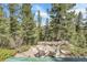 Relaxing outdoor seating area with wicker chairs and stone paving, nestled among trees offering a serene retreat at 33121 Lynx Ln, Evergreen, CO 80439