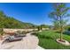 Picturesque backyard featuring a stone patio with lounge chairs, manicured lawn, and tranquil mountain views at 7767 Dante Dr, Littleton, CO 80125