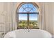 Bathroom featuring a soaking tub with scenic views from the arched window at 7767 Dante Dr, Littleton, CO 80125