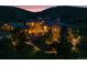 Twilight aerial view of a stone home with manicured landscaping and landscape lighting at 7767 Dante Dr, Littleton, CO 80125