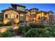 Stunning stone and stucco home with manicured landscaping and a charming front patio area at dusk at 7767 Dante Dr, Littleton, CO 80125