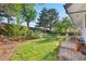 Large, grassy backyard featuring a stone wall, garden beds, and mature trees for shade at 6700 W 80Th Cir, Arvada, CO 80003