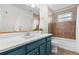 Bathroom featuring blue vanity, quartz countertop, and a shower-tub combination with neutral tile at 6700 W 80Th Cir, Arvada, CO 80003
