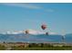 Hot air balloons over scenic landscape with snow capped mountains in background at 565 Twilight St, Erie, CO 80516