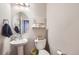 Stylish half bathroom features a pedestal sink, round mirror, and modern decor at 1853 Griffin Dr, Brighton, CO 80601