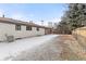 Backyard view shows a patio area, mature trees, leaflitter, some snow, and partial fencing at 11241 W 60Th Ave, Arvada, CO 80004