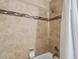 Close-up of a tiled shower and tub featuring a shower head and mosaic accent tile at 3351 S Field St # 150, Lakewood, CO 80227