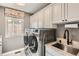 Convenient laundry room featuring modern washer and dryer, sink with granite countertop, and ample cabinet space at 366 Elm St, Denver, CO 80220