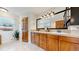 Bathroom featuring dual sinks, wooden cabinetry, a large mirror, and great lighting at 7084 Fox Paw Trl, Littleton, CO 80125