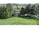 View of a two-story home with a large lawn and mature trees in a green, landscaped front yard at 7084 Fox Paw Trl, Littleton, CO 80125