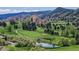 Beautiful golf course with lush greenery, mature trees, a small pond, and the red rock formations in the distance at 7084 Fox Paw Trl, Littleton, CO 80125