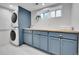 Well-equipped laundry area with sleek washer/dryer, custom blue cabinetry, and ample storage space at 1939 S Sherman St, Denver, CO 80210