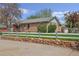 A well-maintained brick home with a white fence, stone wall, and lush front yard at 6895 E 74Th Ave, Commerce City, CO 80022