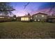 Large backyard at twilight with lush lawn and the house with a sunroom in the background at 12931 E 46Th Ave, Denver, CO 80239
