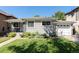 Single-story home with a well manicured lawn, an attached garage, and mature trees in the background at 1627 S Saint Paul St, Denver, CO 80210