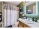 Bathroom with oak vanity, painted green, has a shower curtain, a sink, and a toilet, creating an inviting space at 13255 Holly St # B, Thornton, CO 80241