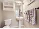 Cozy powder room boasts pedestal sink, tiled floors, fresh towels and built-in shelf for organized storage at 13255 Holly St # B, Thornton, CO 80241