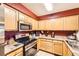 Well-lit kitchen features stainless steel appliances, tile floors and wooden cabinets with modern countertops at 13255 Holly St # B, Thornton, CO 80241