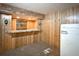 Basement bar featuring unique countertop, wooden walls, and vintage refrigerator, perfect for entertaining at 10440 Gilpin St, Northglenn, CO 80233