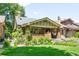 Charming brick bungalow featuring a landscaped front yard and inviting covered porch at 843 Adams St, Denver, CO 80206
