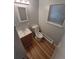 A bright bathroom features wood-look flooring, a modern vanity and toilet, and a window with blinds at 387 Tucson St, Aurora, CO 80011