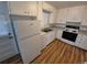 Well-lit kitchen featuring white cabinets, appliances, and wood-look flooring at 387 Tucson St, Aurora, CO 80011