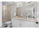 Bathroom featuring double sink vanity, modern fixtures, a large mirror, and tiled shower with glass door at 2140 S Ash St # 101, Denver, CO 80222