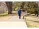 A person walks a dog along a tree-lined walking path in a peaceful park setting at 2140 S Ash St # 101, Denver, CO 80222