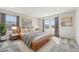 Bright main bedroom with a wooden bed frame, soft gray carpet, and two large windows at 21411 E 60Th Ave, Aurora, CO 80019