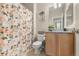 Cozy bathroom featuring a floral shower curtain, tile flooring, and wooden vanity at 848 Sagebrush Dr, Brighton, CO 80603