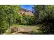 Inviting backyard area with mature trees and a charming bench, perfect for relaxing outdoors at 2602 Hidden Valley Road, Sedalia, CO 80135