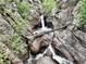 A scenic waterfall flows through a rocky canyon, highlighted by a fallen log at 2602 Hidden Valley Road, Sedalia, CO 80135