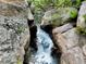 Scenic view of a small waterfall cascading down rocks and lush foliage at 2602 Hidden Valley Road, Sedalia, CO 80135