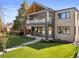Modern two-story home featuring a covered balcony, gray siding, brick accents, and a well-manicured front lawn at 2610 N Monroe St, Denver, CO 80205