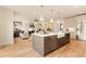 Open-concept kitchen featuring a large island, stainless steel appliances, and hardwood floors, flowing into living room with fireplace at 2610 N Monroe St, Denver, CO 80205