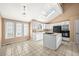 Bright kitchen with white cabinetry, center island, skylight, and black appliances at 9465 W 77Th Dr, Arvada, CO 80005