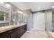 Bathroom featuring double sinks, dark wood cabinets, tile floors, and a tiled shower with glass door at 19080 E Low Cir, Aurora, CO 80015