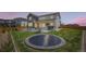 Spacious backyard featuring a trampoline, fire pit, outdoor dining area, and lush green lawn at 6255 Kenzie Cir, Castle Pines, CO 80108