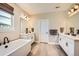 Bright bathroom featuring a soaking tub, dual sinks, white cabinets, and neutral flooring at 6255 Kenzie Cir, Castle Pines, CO 80108
