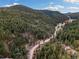 Stunning aerial perspective of the property, emphasizing its harmonious integration with the surrounding forested landscape at 7559 S Turkey Creek Rd, Morrison, CO 80465