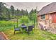 This backyard features an outdoor dining set, grass, trees and a rock feature on house at 7559 S Turkey Creek Rd, Morrison, CO 80465