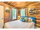 Stylish bedroom with wood paneled walls, plush bedding, and natural light creates a serene and inviting atmosphere at 7559 S Turkey Creek Rd, Morrison, CO 80465