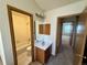 A bathroom featuring a single vanity, neutral paint, wood trim and a door that shows the carpeted bedroom at 10716 Foxwood Ct, Parker, CO 80138